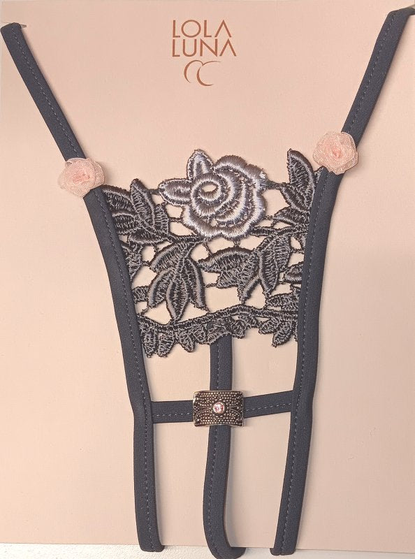 Mini string noir ouvert à l’entrejambe, brodé et décoré de petites roses, avec un bijou délicatement positionné.