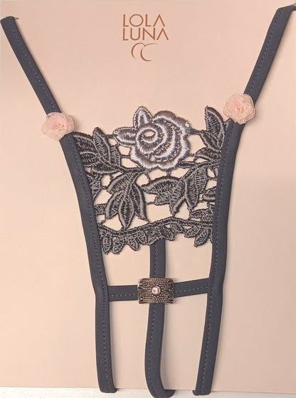 Mini string noir ouvert à l’entrejambe, brodé et décoré de petites roses, avec un bijou délicatement positionné.