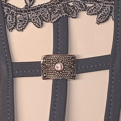 String noir glamour ajouré, détails de broderies et petites roses, agrémenté d’un bijou placé avec élégance.